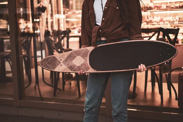 Ragazza è in piedi vicino caffè con longboard — Foto Stock