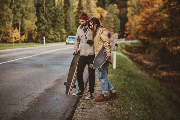 素敵なカップルは、道路上でヒッチハイクしています — ストック写真