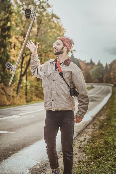 O tipo está a atirar o seu longboard para a estrada — Fotografia de Stock