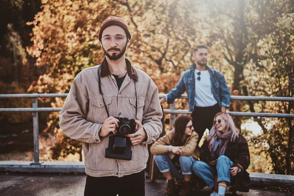 Joven barbudo hipster con cámara y sus amigos — Foto de Stock