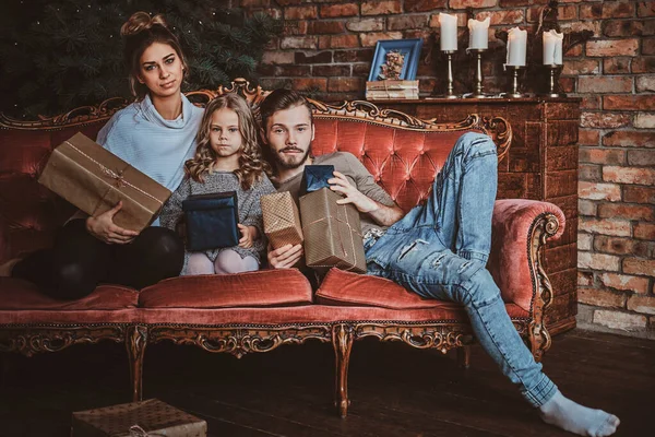 Jovem família está relaxando no sofá retro na véspera de Ano Novo — Fotografia de Stock