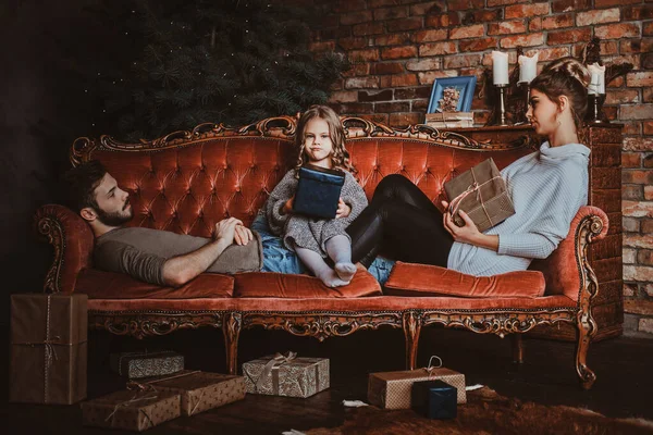 Jovem família está relaxando no sofá retro na véspera de Ano Novo — Fotografia de Stock