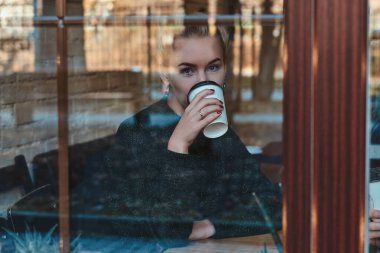 Güzel bir kadın kahvecide içki içiyor.