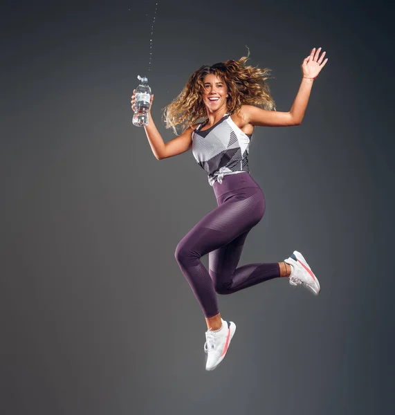 Portrait de femme heureuse sautant avec une bouteille d'eau — Photo
