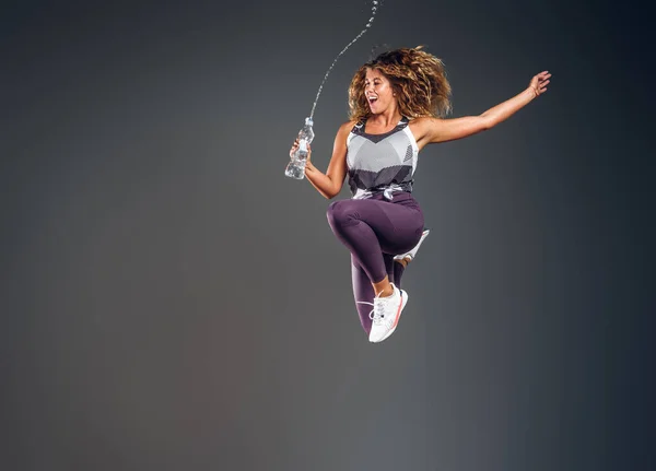Портрет щасливої жінки, що стрибає з пляшкою води — стокове фото