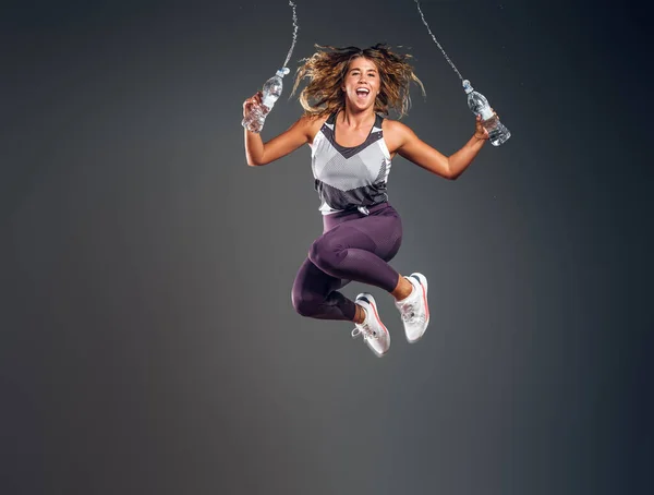 Portret szczęśliwej kobiety skaczącej z butelką wody — Zdjęcie stockowe