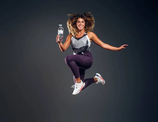 Retrato de mujer feliz saltando con botella de agua —  Fotos de Stock