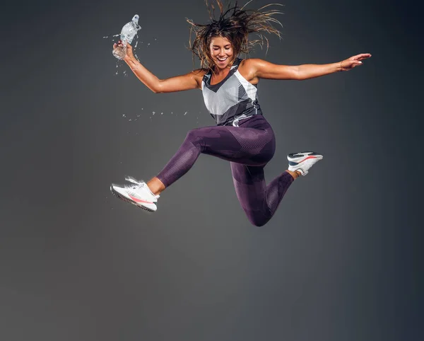 Ritratto di donna felice che salta con bottiglia d'acqua — Foto Stock