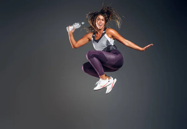 Retrato de mulher feliz pulando com garrafa de água — Fotografia de Stock