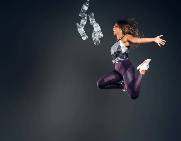 Retrato de mujer feliz saltando con botella de agua — Foto de Stock