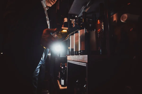 Homme élégant en costume à la cave à vin avec bouteille de vin — Photo