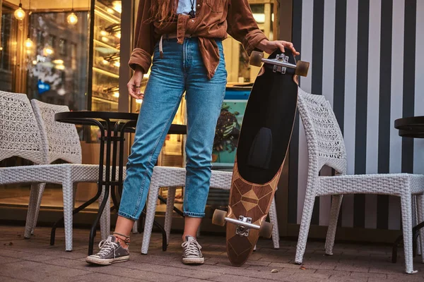 Menina está de pé perto de café com longboard — Fotografia de Stock