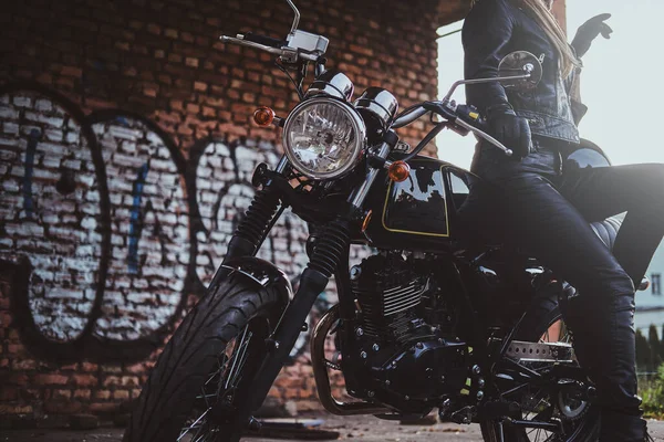 Female biker in black with her motorbike next to graffity wall — Stock Photo, Image