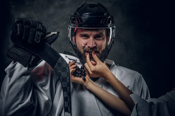 Woman is feedeng hockey player with grape — Stock Photo, Image