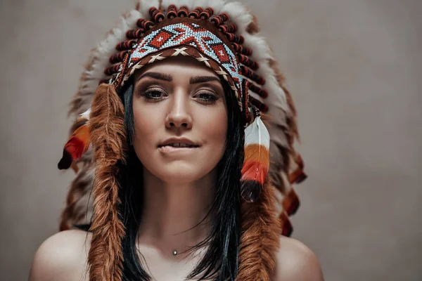 Aantrekkelijke vrouw poseren naakt in studio dragen indiaanse veer hoofddeksel — Stockfoto