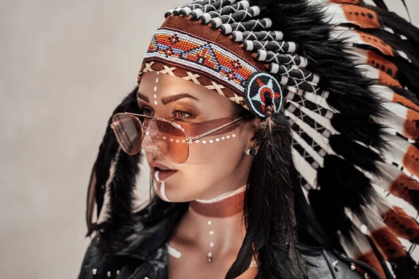 Donna attraente posa in studio e indossa copricapo tribale e trucco orientale — Foto Stock