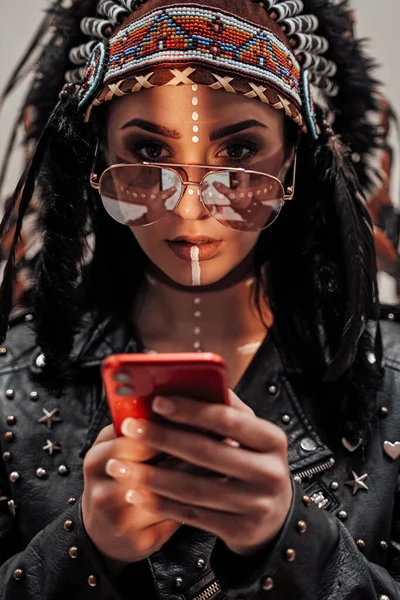 Portrét stylové dívky s rodilým americkým kmenovým make-upem a cyklistickým oblečením s chytrým telefonem — Stock fotografie