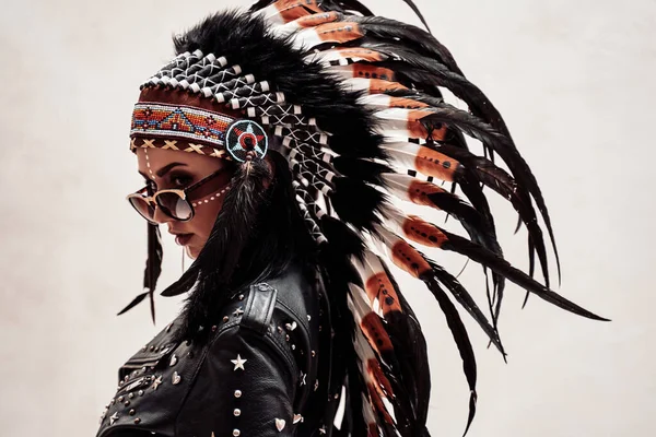 Native American model looking from behind, wearing leather jacket and feather headwear — Stock Photo, Image