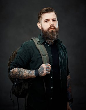 Seyahat ve eğitim kavramı. Stüdyoda sırtında sırt çantası olan sakallı hippi.