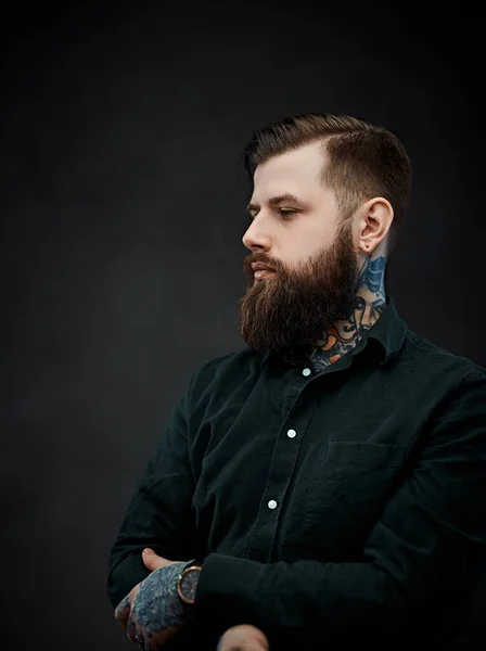 Jóképű tetovált férfi elegáns frizurával pózol a sötét háttér — Stock Fotó