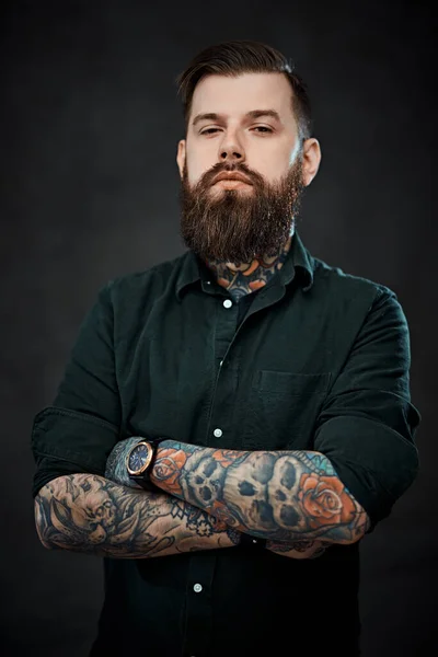 Bonito homem tatuado com corte de cabelo elegante posando em um fundo escuro — Fotografia de Stock
