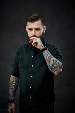 Sigara içen yakışıklı dövmeli bir hippinin stüdyo portresi.