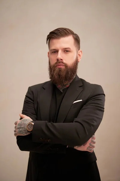 Homem de negócios barbudo em um elegante terno preto posando em um estúdio — Fotografia de Stock