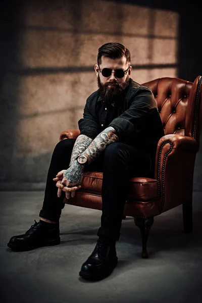 Cool jeune homme barbu assis sur une chaise vintage en studio — Photo