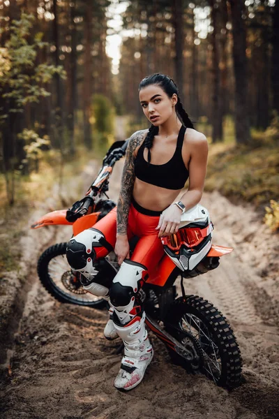 Žena závodník na sobě motokros oblečení s polonahý trup sedí na kole v lese — Stock fotografie