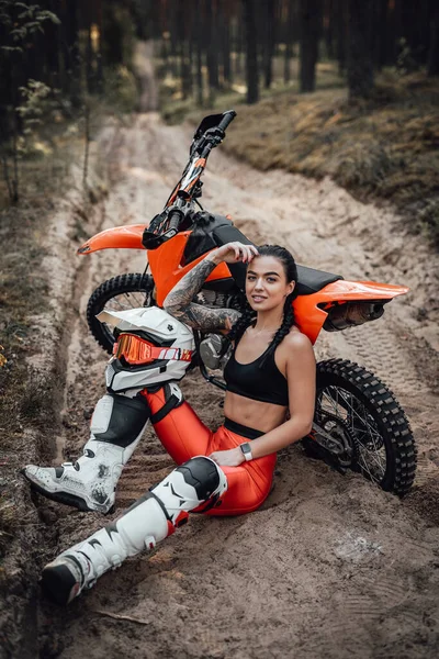 Encantadora joven corredor femenino con el torso semi desnudo sentado arena junto a su bicicleta en el bosque — Foto de Stock