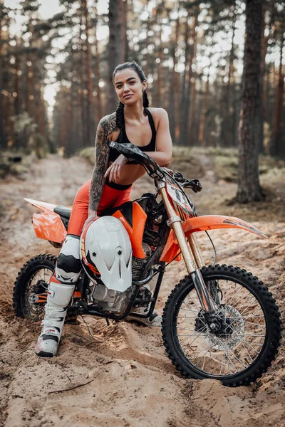 Charmoso jovem piloto feminino com tronco semi nu sentado em sua bicicleta na floresta — Fotografia de Stock