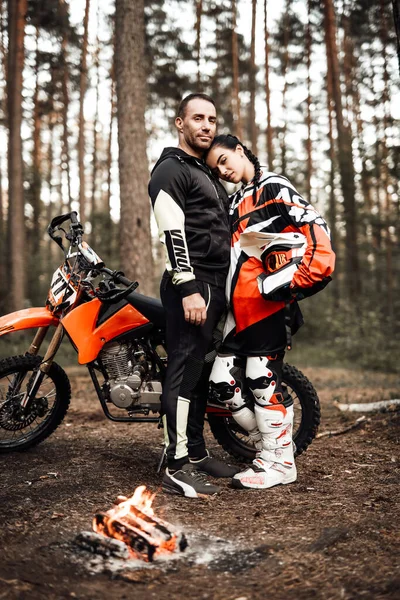 Çiftler ormanda motosiklet ve şenlik ateşinin yanında sarılırlar. — Stok fotoğraf
