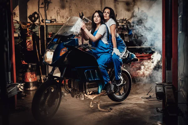 Δύο γυναίκες μηχανικός κάθεται σε sportbike σε αυθεντικό γκαράζ εργαστήριο — Φωτογραφία Αρχείου