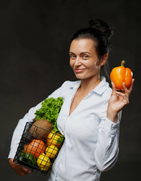 Donna di mezza età tiene un cesto di verdure fresche e frutta, sorridente e guardando su una macchina fotografica — Foto Stock