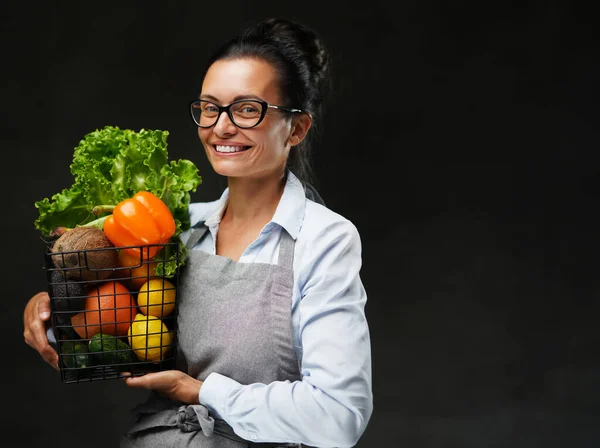 Portrait d'une agricultrice d'âge moyen dans un tablier tient un panier de légumes et de fruits frais — Photo