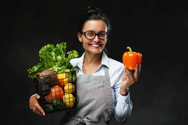 Ritratto di contadina di mezza età in grembiule regge un cesto di frutta e verdura fresca — Foto Stock