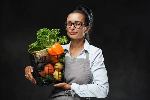 Ritratto di una donna felice di mezza età in grembiule tiene un cesto di verdure fresche e frutta — Foto Stock