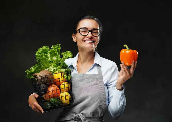 Ritratto di contadina di mezza età in grembiule regge un cesto di frutta e verdura fresca — Foto Stock