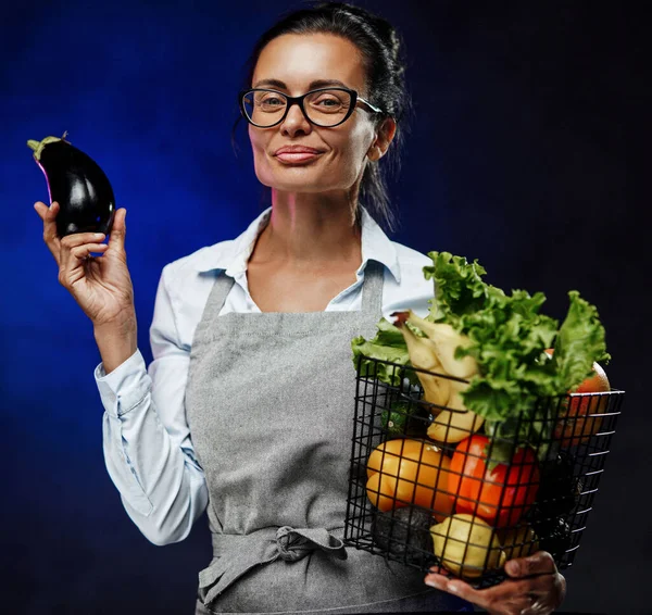 Önlüklü orta yaşlı bir kadın çiftçinin portresi bir sepet taze sebze ve meyve tutuyor. — Stok fotoğraf