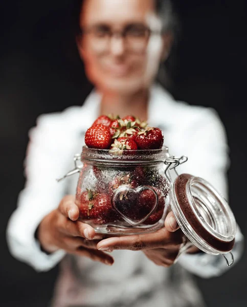 Nahsicht auf ein nasses Glas mit reifen Erdbeeren. Chef hält ein Glas mit frischen roten saftigen Beeren — Stockfoto