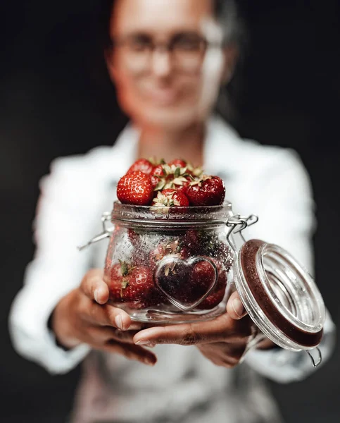 Close Up vista su un bicchiere bagnato con fragola matura. Lo chef tiene un bicchiere con bacche succose rosse fresche — Foto Stock