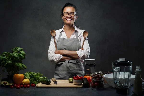 キッチンで新鮮な野菜とテーブルの横にポーズ成熟した女性の笑顔 — ストック写真