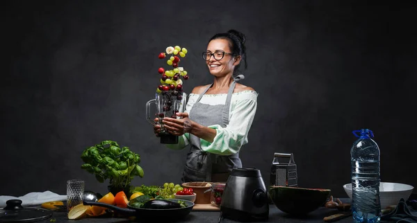 幸せな中年女性シェフトス新鮮な果物で空気中のミキサーからキッチン — ストック写真