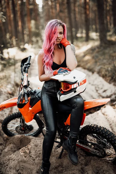 Modern tatuerad hipster flicka med ljust rosa hår sitter på sin motocross cykel i skogen — Stockfoto