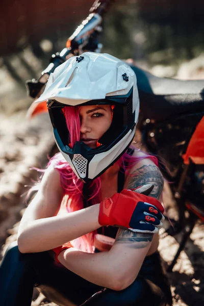 Schöne Hipster-Mädchen mit einer Tätowierung auf dem Arm und rosa Haare bedecken das Auge in Schutzhelm — Stockfoto