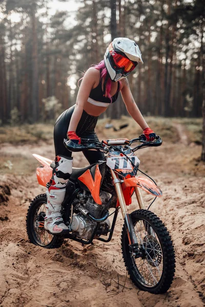 Güvenli kasklı genç bayan motokros yarışçısı off road macerasında motosikletine biniyor. — Stok fotoğraf