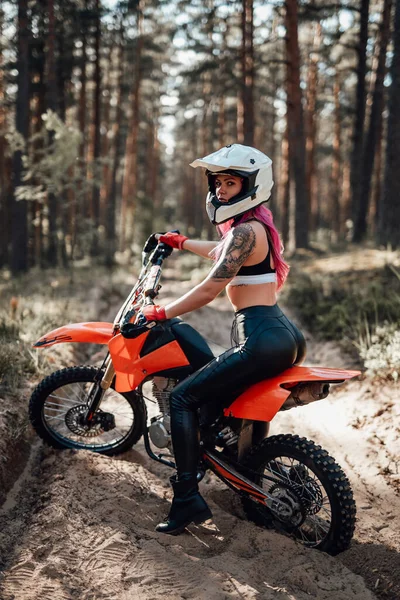 Joven chica atleta tatuada con pelo rosa cabalgando en su motocicleta en la aventura fuera de la carretera —  Fotos de Stock