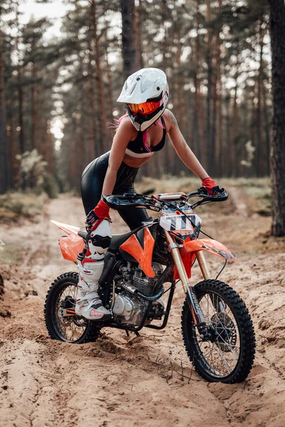 Güvenli kasklı genç bayan motokros yarışçısı off road macerasında motosikletine biniyor. — Stok fotoğraf