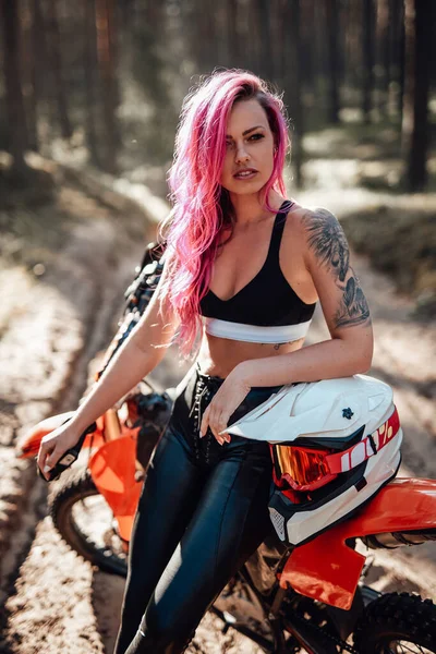 Nowoczesny wytatuowany hipster dziewczyna z jasnoróżowymi włosami siedzi na motocross rower w lesie — Zdjęcie stockowe