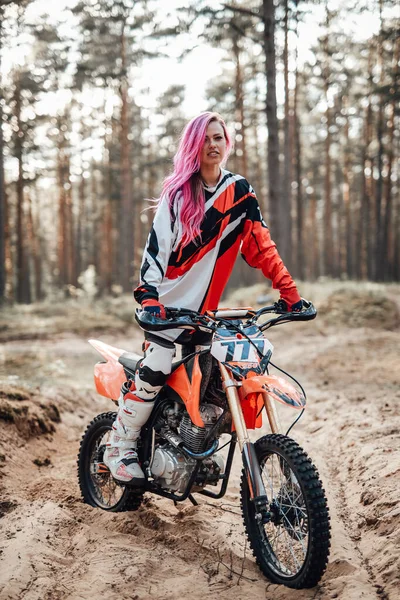 Motokros takımında pembe saçlı genç yarışçı kız off road macerasında motosikletinin üzerinde oturuyor. — Stok fotoğraf